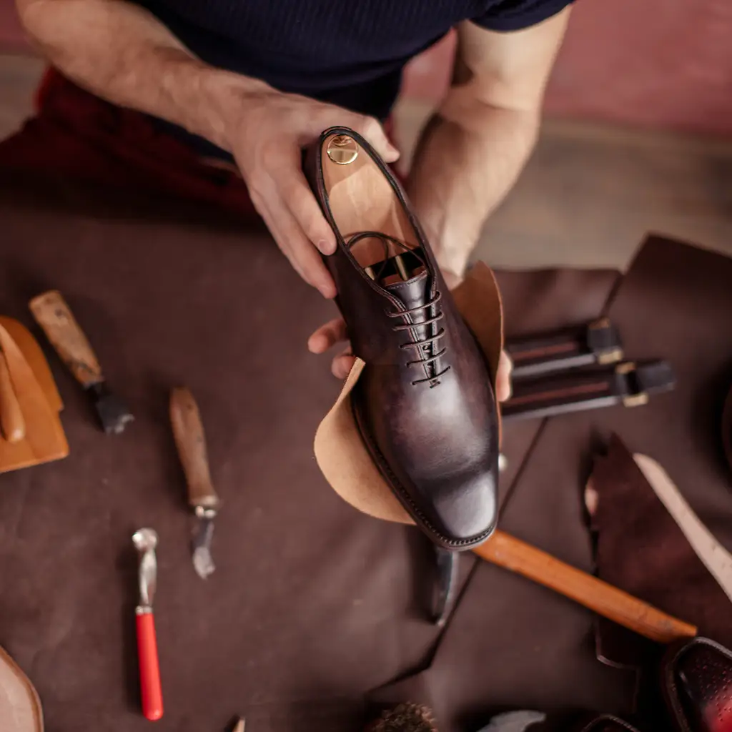 Schuhmacher mit Maßschuhen